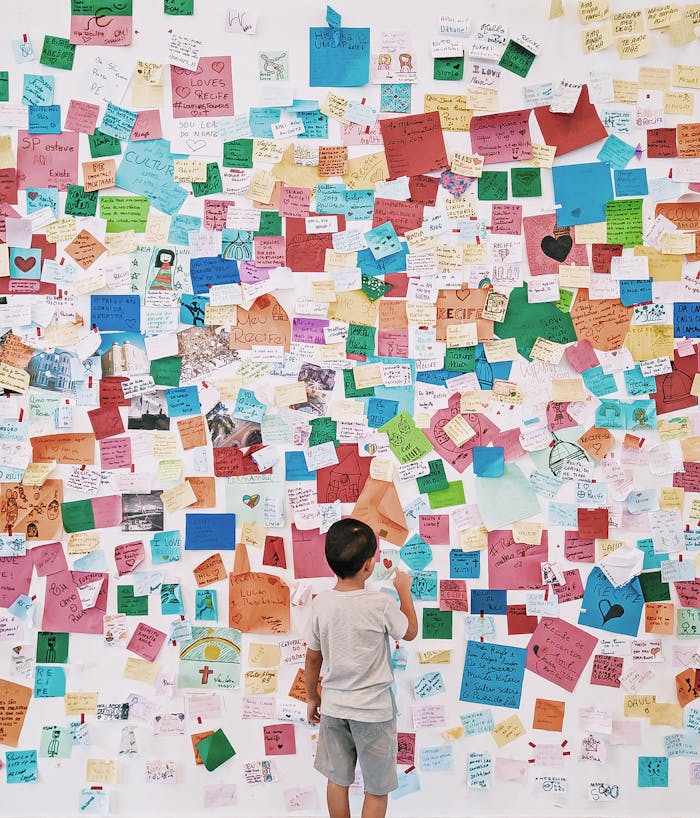 pexels-photo-5294045 A child stands before a wall covered with colorful notes and messages, exploring creativity and expression.
