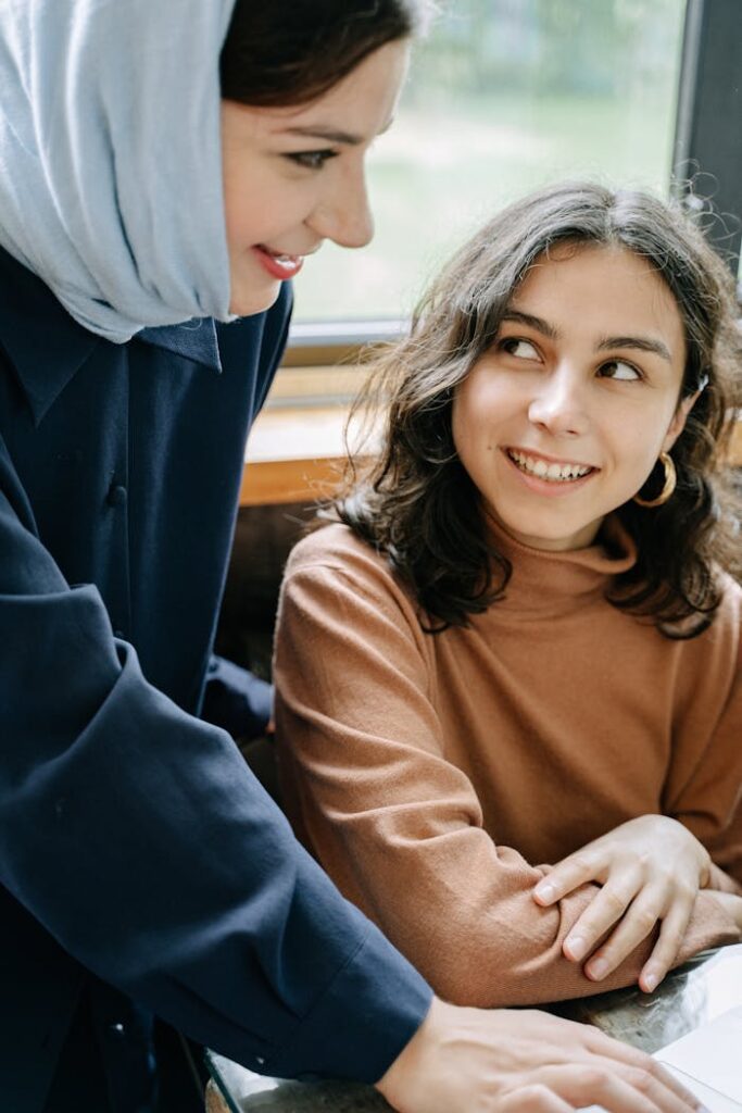pexels-photo-5428989 Two women smiling warmly and engaging indoors, capturing friendly and diverse interaction.