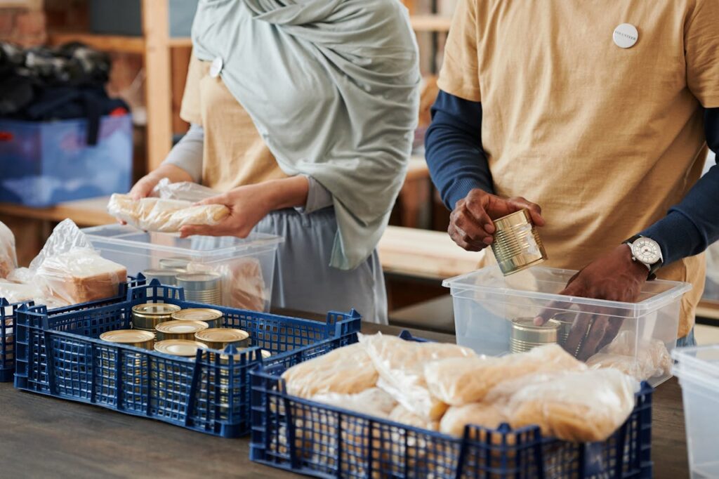 pexels-photo-6995201 Adults sorting food donations in containers for charity. Community service effort indoors.